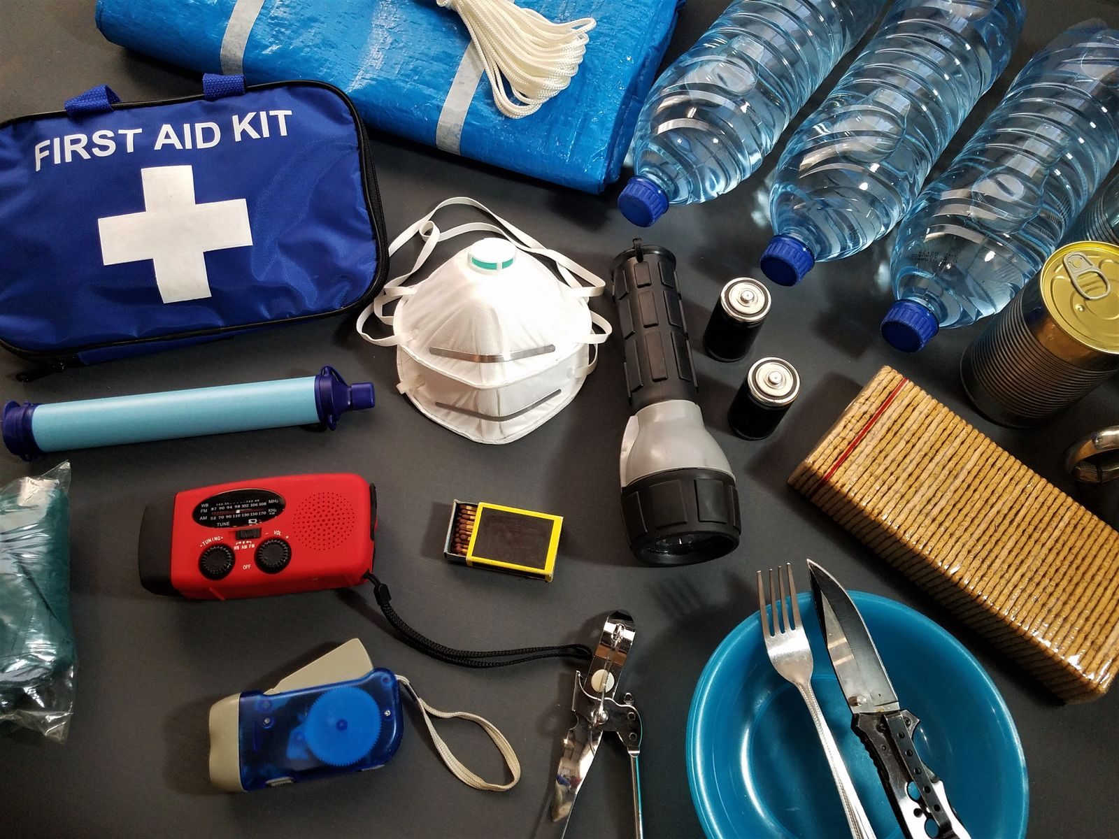 An emergency kit laid out flat: water, torch, radio, first aid and documents