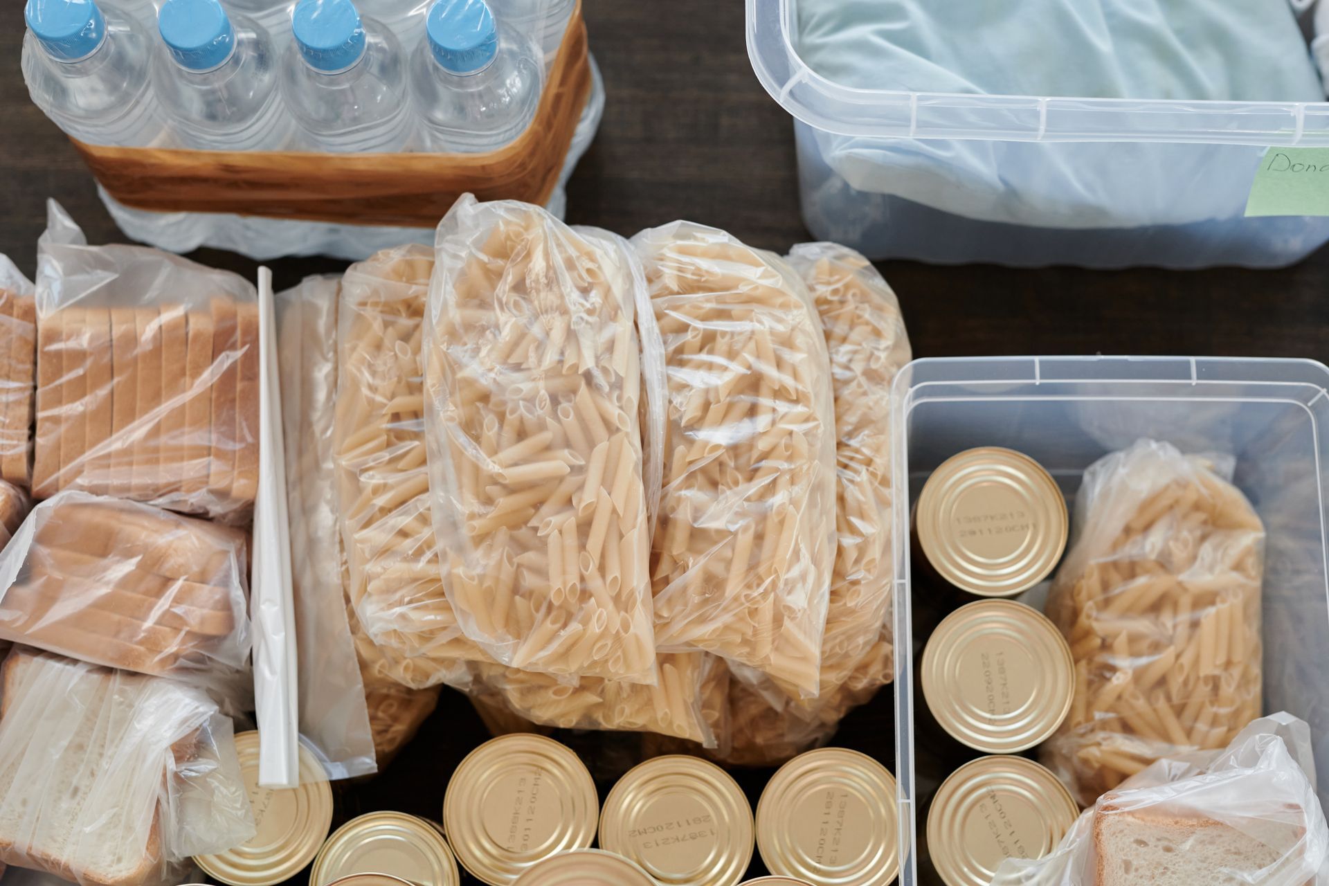 Shelf-stable food and bottled water packed into clear storage tubs, seen from above